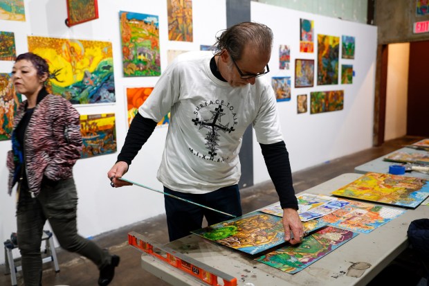 Brian Eder, co-owner at Anno Domini gallery, picks a painting by Zack Luchetti for a tribute exhibition called "Illuminate the Wolves" at the gallery in downtown San Jose, Calif., on Thursday, March 2, 2023. Luchetti grew up in Oakland and attended to San Jose State and Cal State Hayward. He died from colon cancer in 2021. (Nhat V. Meyer/Bay Area News Group)