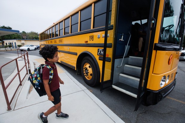 In the parking lot of the closed Terrell Elementary school, Gio Naughton, 7, walks up to a school bus to take him to his new school on Friday, Aug. 7, 2026, in San Jose, Calif. Terrell Elementary closed along with four other campuses earlier this year. Naughton now attends Rachel Carson Elementary. (Dai Sugano/Bay Area News Group)