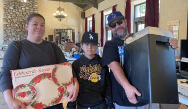 two adults and a teenage boy hold garage sale finds in a large hall