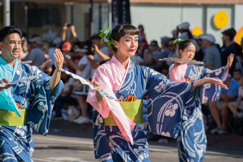 A Bando-ryu dancer opens her left palm, with a folding fan in her right hand.