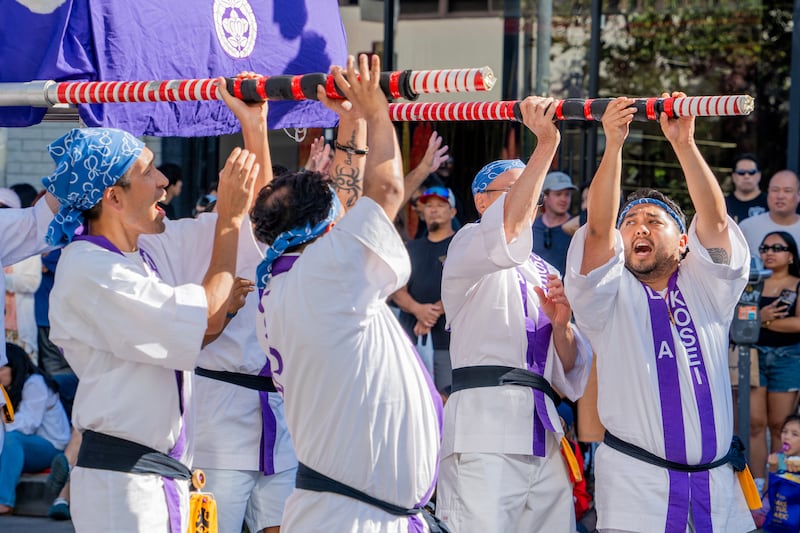 Paraders with Rissho Kosei Kai collectively chant while carrying a mandō, a tall illuminated lantern hung with rows of artificial cherry blossoms.