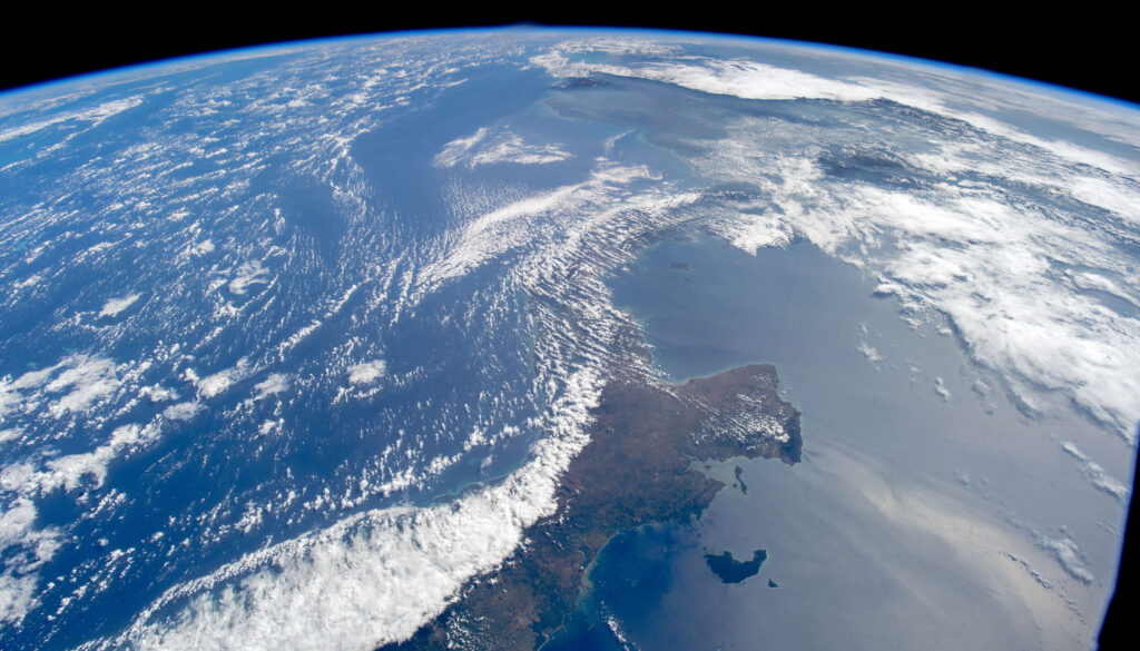 the curved edge of a blue Earth with white clouds seen from space