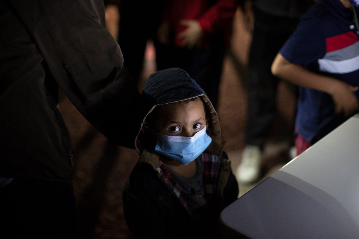An unaccompanied minor looks up as he waits to answer questions from a U.S. Border Patrol agent at an intake site after he was smuggled on an inflatable raft across the Rio Grande river in Roma, Texas, Wednesday, March 24, 2021.