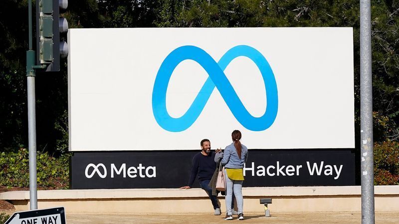 FILE - People talk near a Meta sign outside of the company's headquarters in Menlo Park, Calif., March 7, 2023. (AP Photo/Jeff Chiu, File)