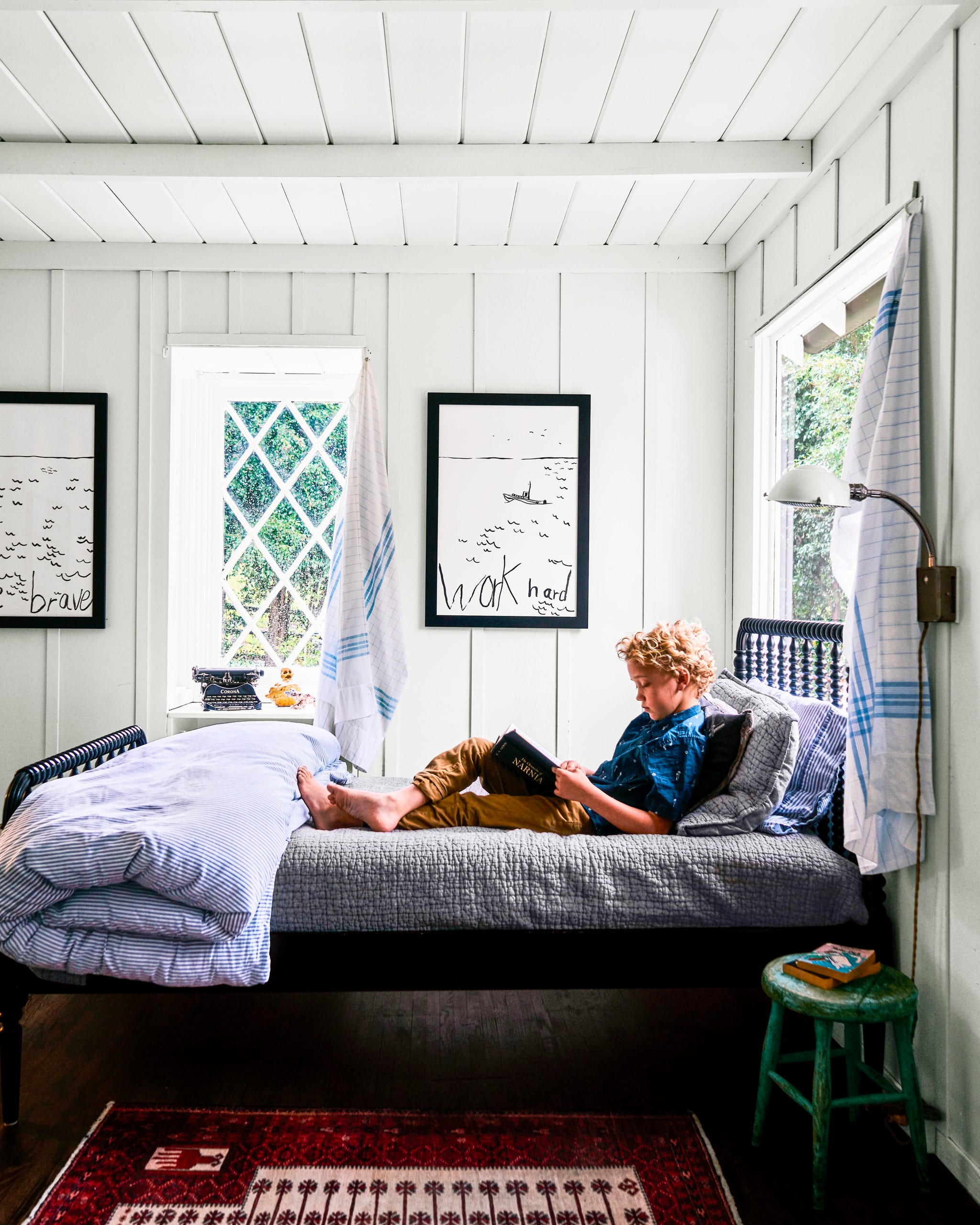 boy sitting on bed with blue bedding beneath walls painted white boy sitting on bed with blue bedding beneath walls painted white