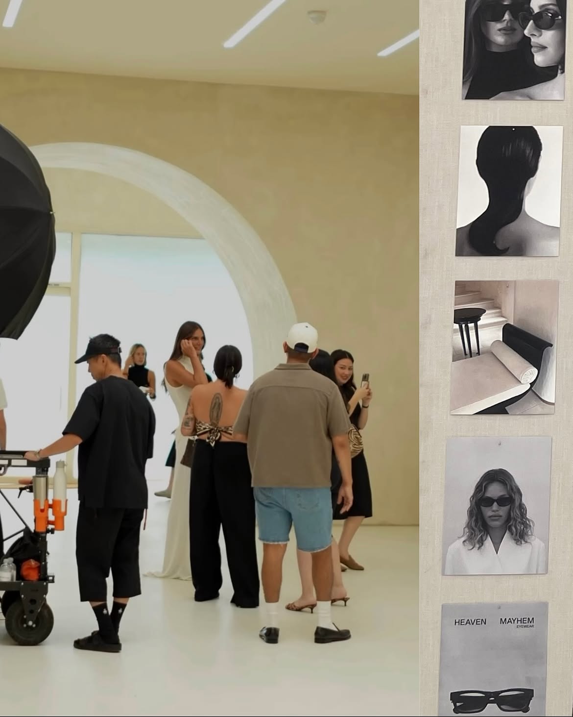 Group of people in a gallery with large arched window, some taking photos, others talking, and a person with a stroller.