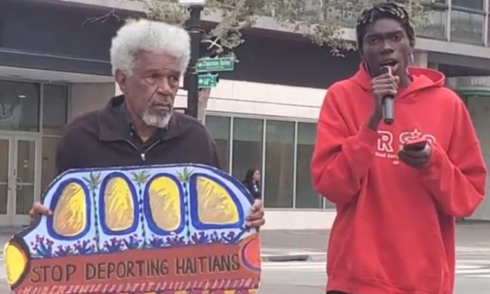 Activists Gerald Smith and Romaine Charite at 14th and Broadway in downtown Oakland near City Hall protest in support of Haitian immigrant rights. Photo by Carla Thomas