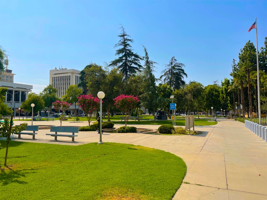 Courthouse Park in Fresno, California, with green lawns, paths, trees, and buildings.