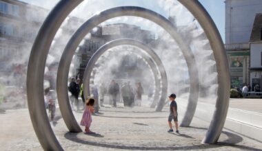 An example of public art misters in the form of large vertical rings with children running through them.