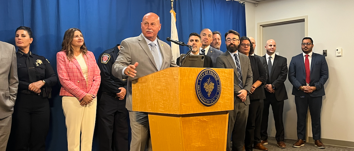 man at podium with people behind him