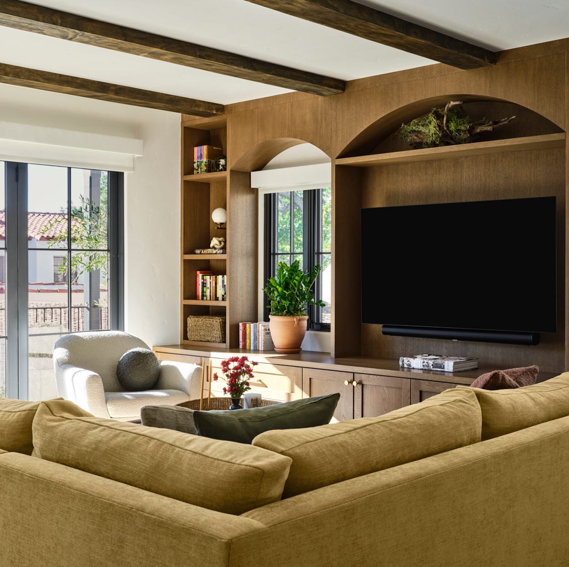 a spacious living room features a large, beige sectional sofa positioned to face a mounted flat screen television