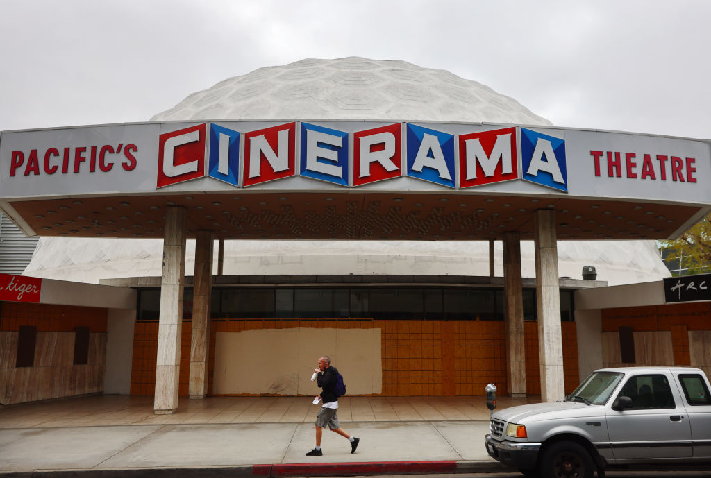 A person walks past a boarded up entrance at the famed Cinerama Dome at the shuttered ArcLight Hollywood movie theater on April 13