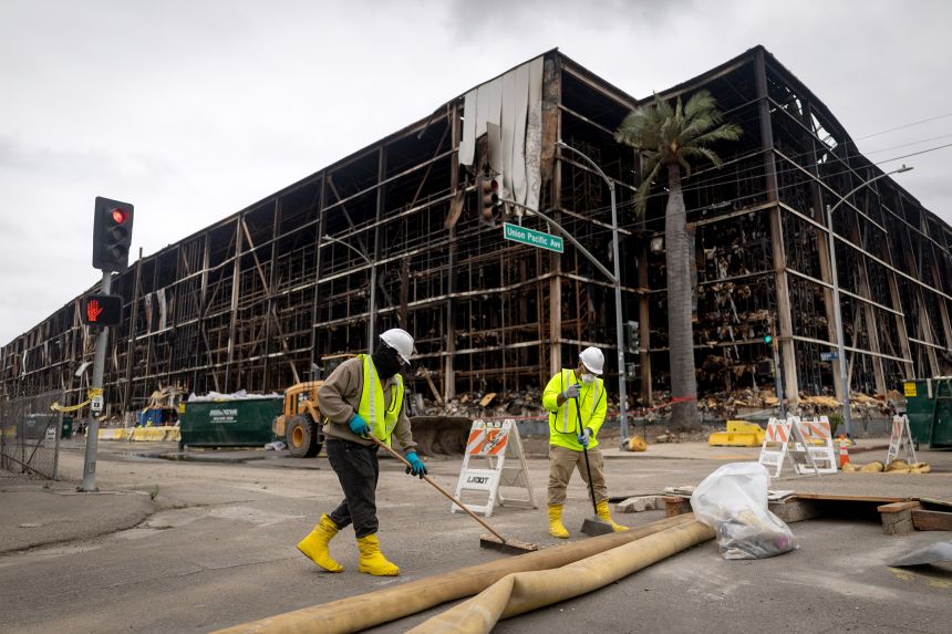 A crew cleans up after a massive warehouse fire in the Boyle Heights neighborhood on Monday, June 29, 2026, in Los Angeles, California.