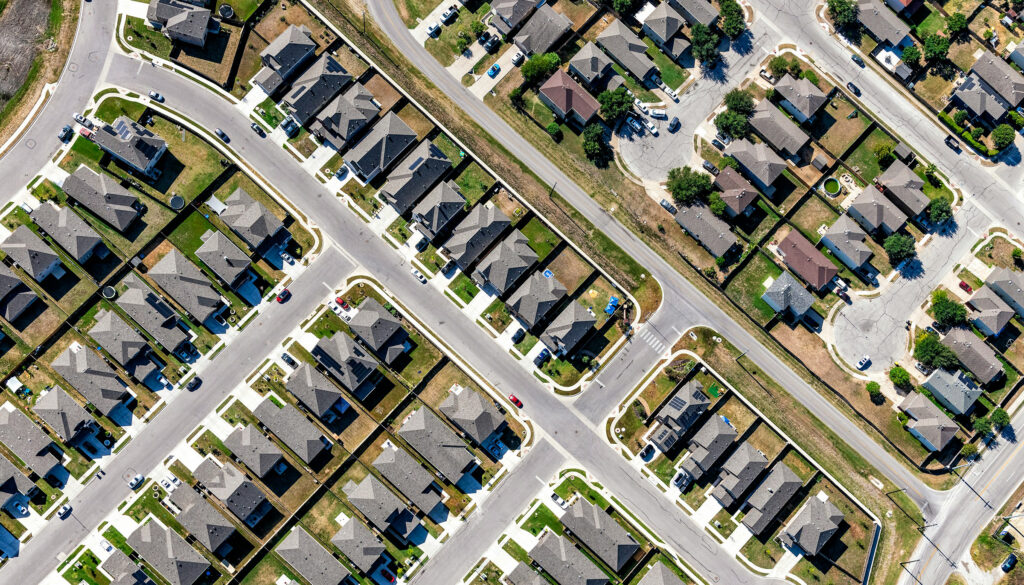 An aerial shot of a modern housing development, with homes built side by side among a diagonal grid of streets and cul-de-sacs