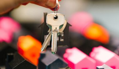 A pair of house keys dangling over multicolored miniature home figures