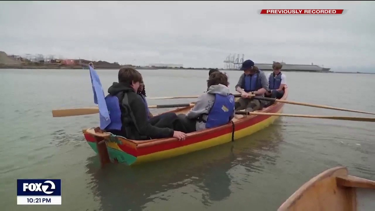 Students launch boat into the bay, they built themselves