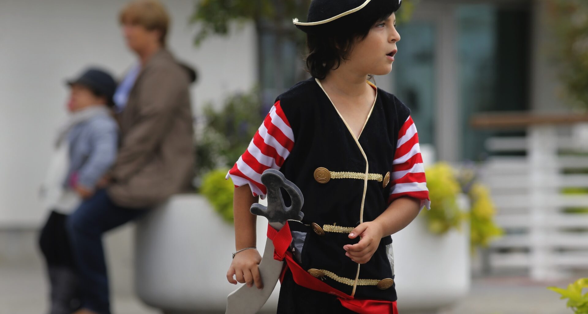 A young boy dressed as a pirate glances around curiously.