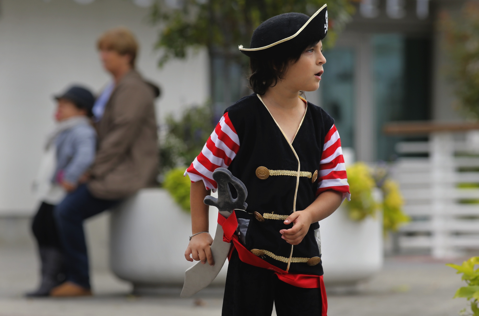 A young boy dressed as a pirate glances around curiously.
