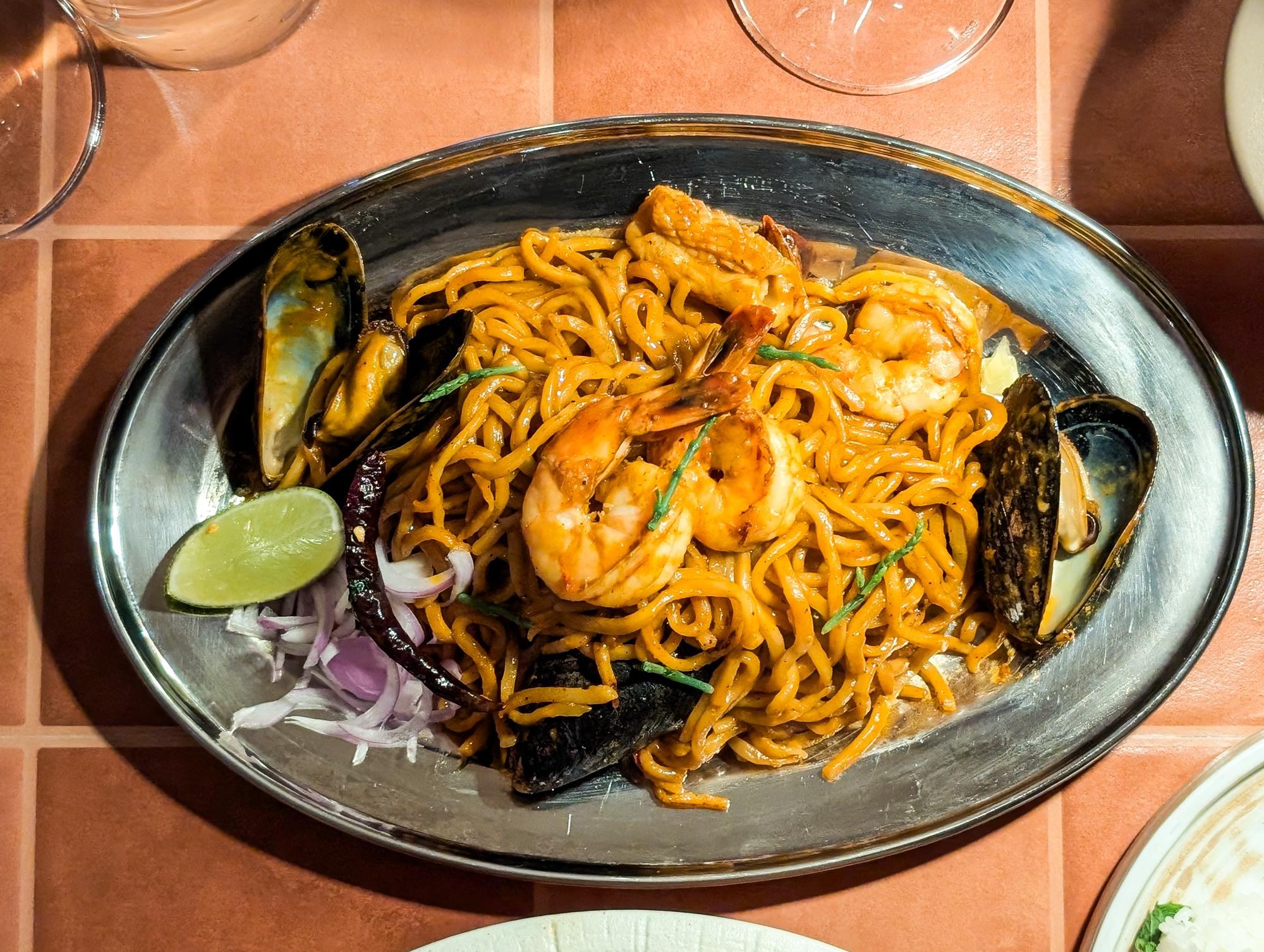A plate of noodles with shrimp, mussels, and a wedge of lime at Saam in San Francisco.
