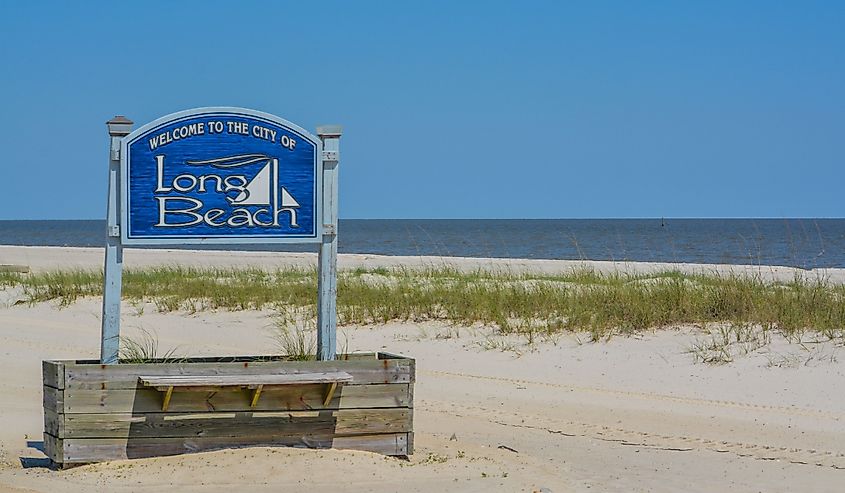 Welcome sign at Long Beach, Mississippi, with the coast behind it.
