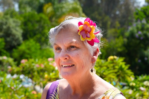 Stacy Atkinson, co-owner of Atkinson Plumeria on Mount Helix, displays a floral hair piece evoking the aloha spirit using flowers grown at the farm. She teaches classes on making leis and arrangements. (Nelvin C. Cepeda / The San Diego Union-Tribune)