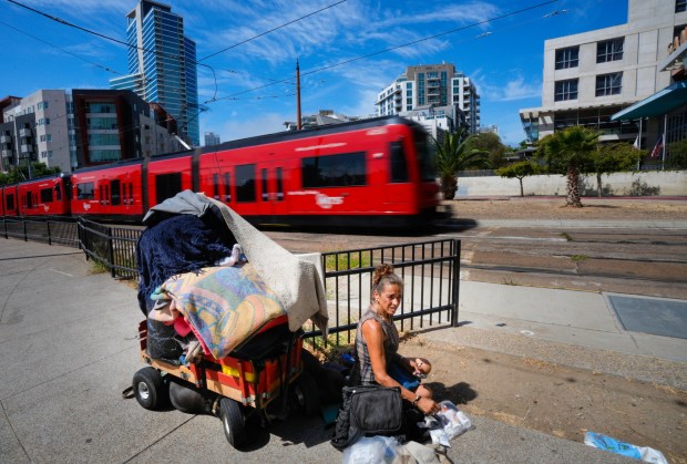 Jennifer Novarro, 55 sits with her personal belongings just outside the San Diego Central Library on a hot Thursday morning. While San Diego is experiencing a heatwave, Novarro, who has lived on the street since 2022, cannot go inside the library, which has air conditioning to provide relief from the heat, because she has nowhere to securely store her belongings. (Nelvin C. Cepeda / The San Diego Union-Tribune)