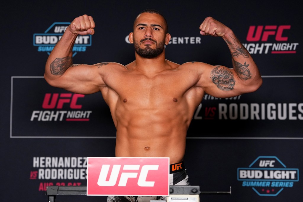 Vitor Petrino poses with flexed arms on a scale during the UFC Fight Night weigh-in.