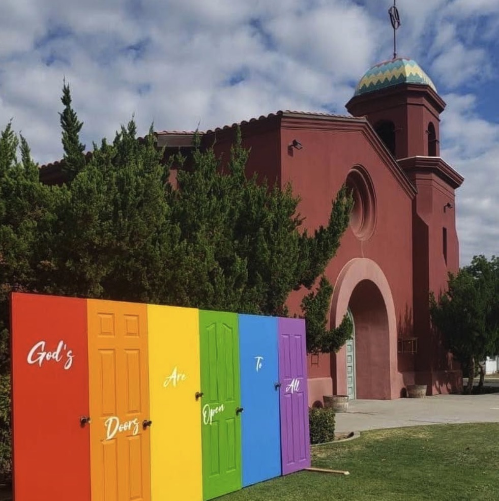 The Big Red Church of Fresno with a display of rainbow-colored doors that spell out "God's Doors Are Open To All."