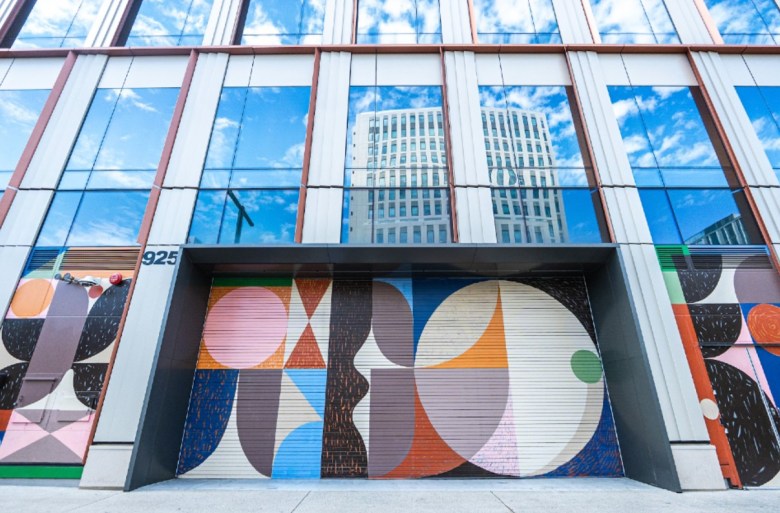 The facade of a downtown structure with colorful geometric art decorating the street-level winedows.