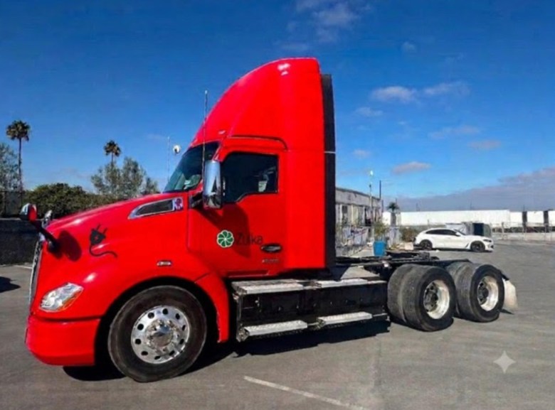 A semi-truck cab parked in a large lot.