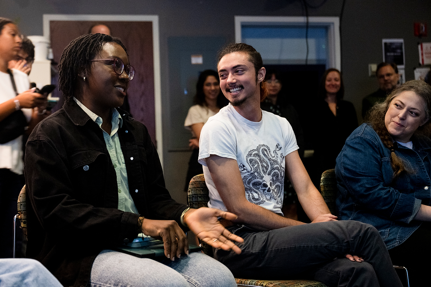 Students seated together in a dim studio space, facing forward during a class session.