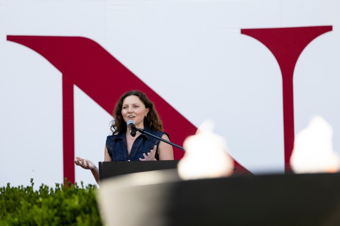 Kelsey Lawler speaks at a podium, framed against a large Northeastern "N" logo.