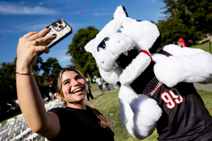 A student takes a selfie with Paws the mascot.