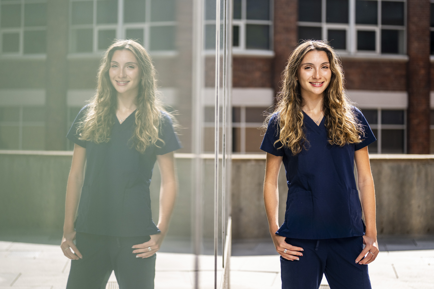 Sophie Gandsas, a behavioral neuroscience student, stands outdoors on Northeastern's campus wearing navy scrubs.