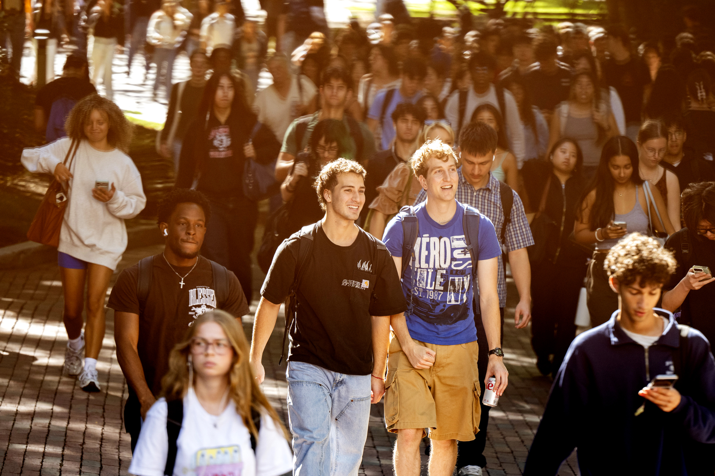 A crowd of students walk through campus.