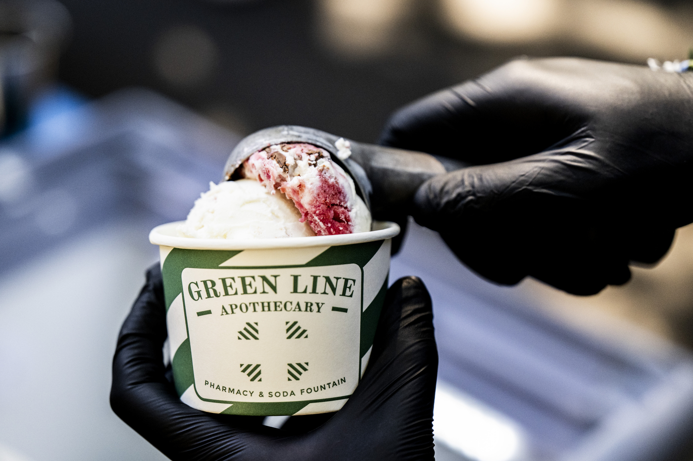 Close-up of a hand serving a cup of Cherry Fudge Swirl ice cream.