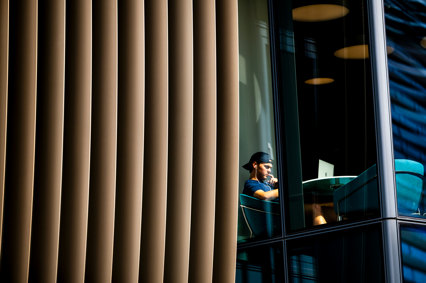 A student studies at a desk inside ISEC, viewed through the building's exterior louvered panels.