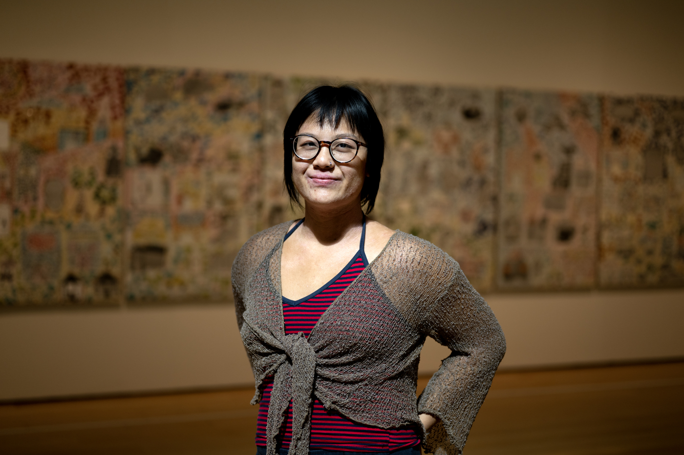 Kelly Chen, a Northeastern alum, stands in front of her mosaic artwork on display in a museum gallery.