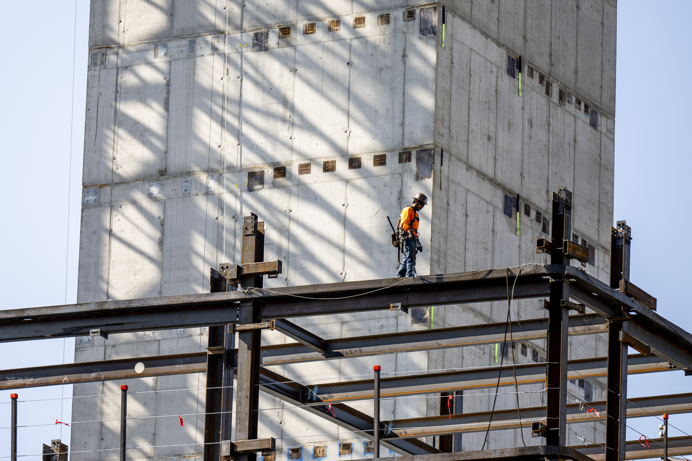 A construction worker stands on scaffolding beside a tall concrete building facade at 840 Columbus Avenue.