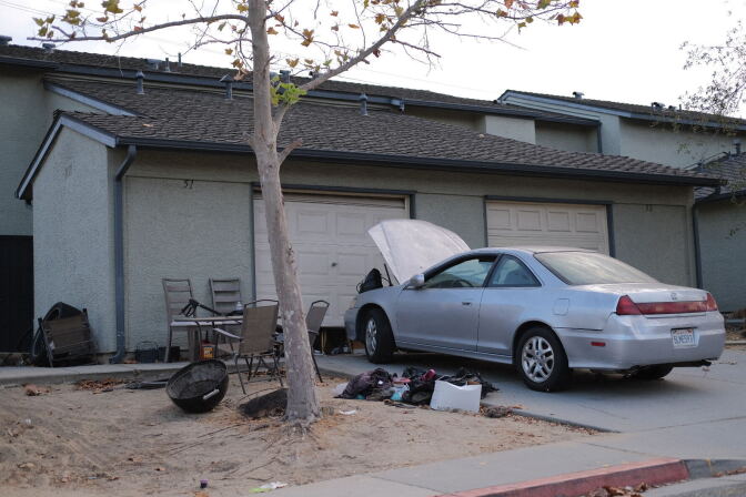 A silver car with a popped hood is parked in a driveway outside of a townhome in San Pedro.