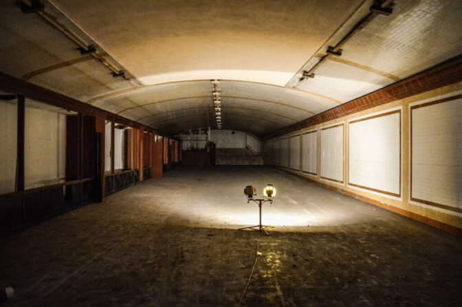 A tunnel dimly lit by a work light on the floor.