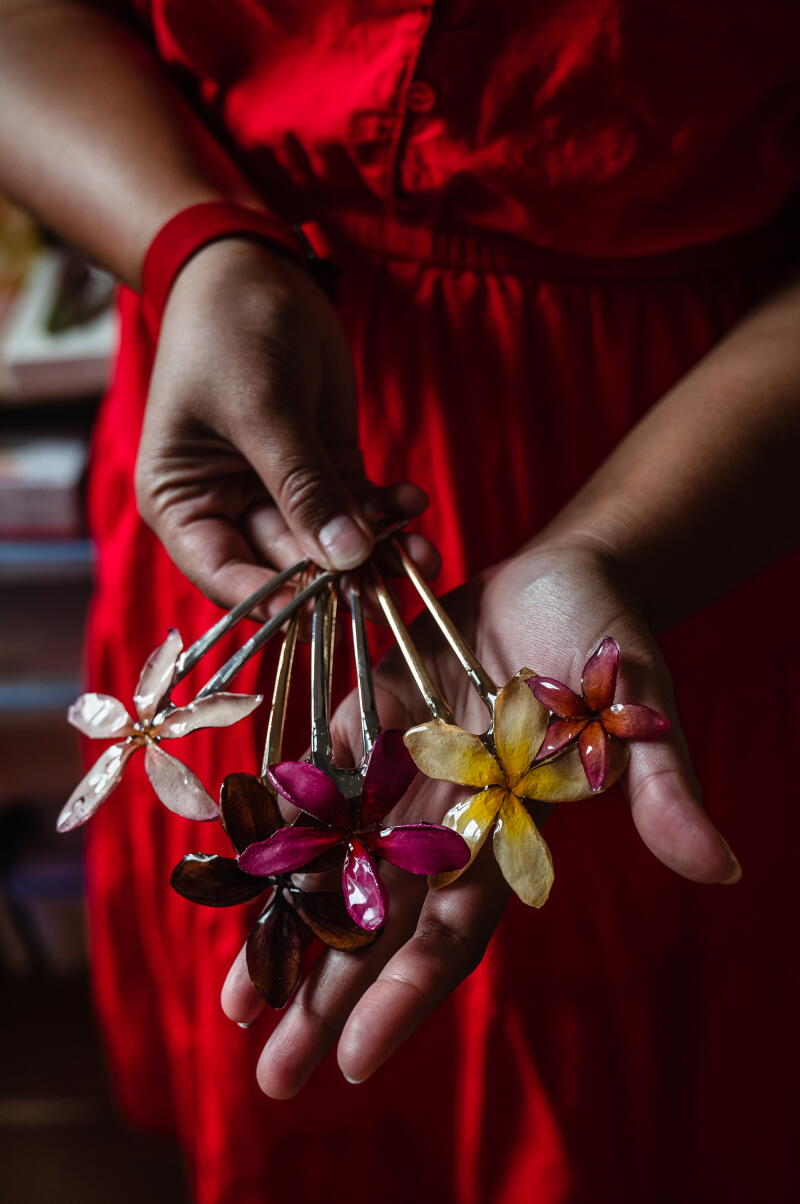 Plumeria hair pins that she designed using real preserved flowers into resin.