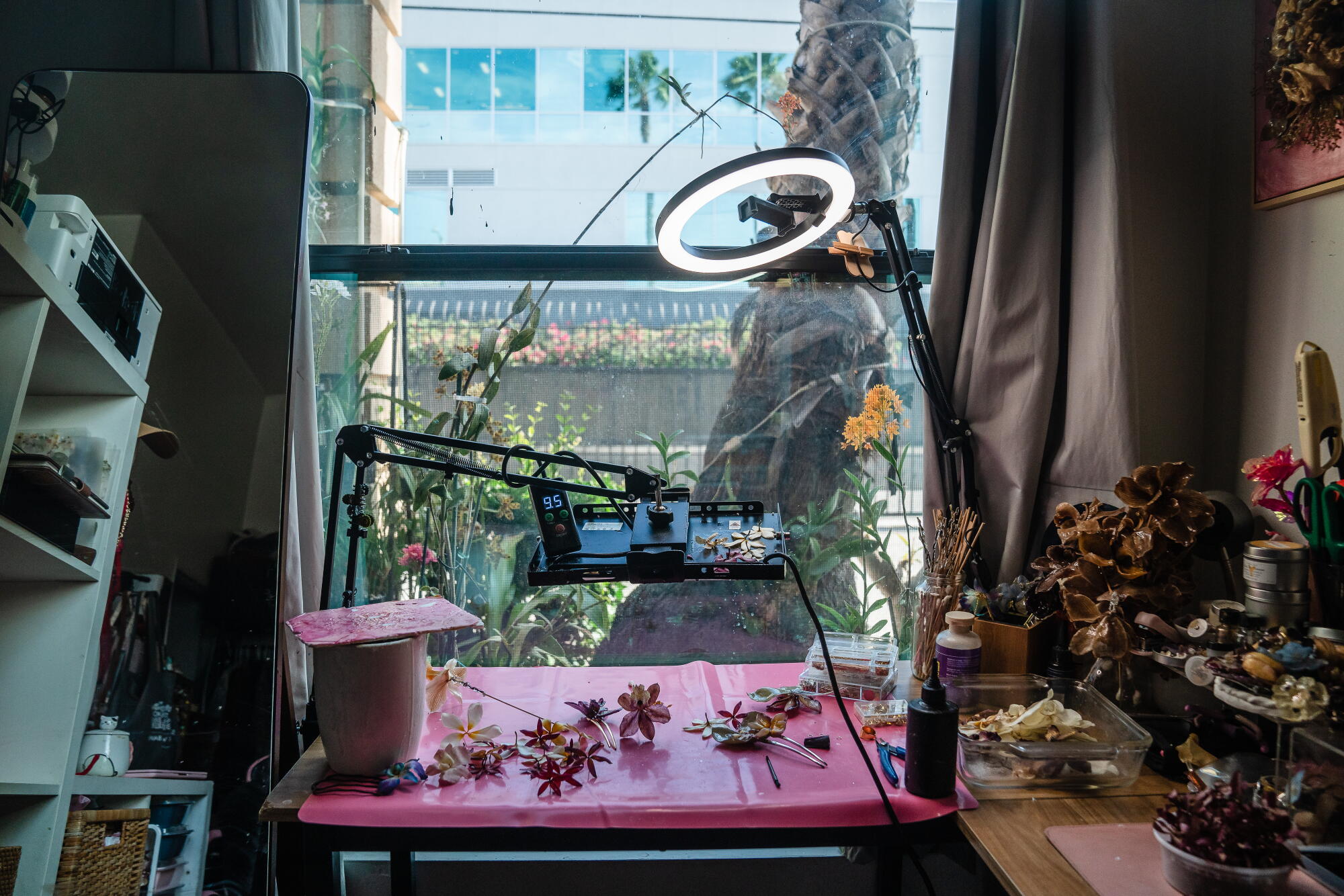 At a small table, Vidanska works on her floral accessories, with a view of her small patio garden.