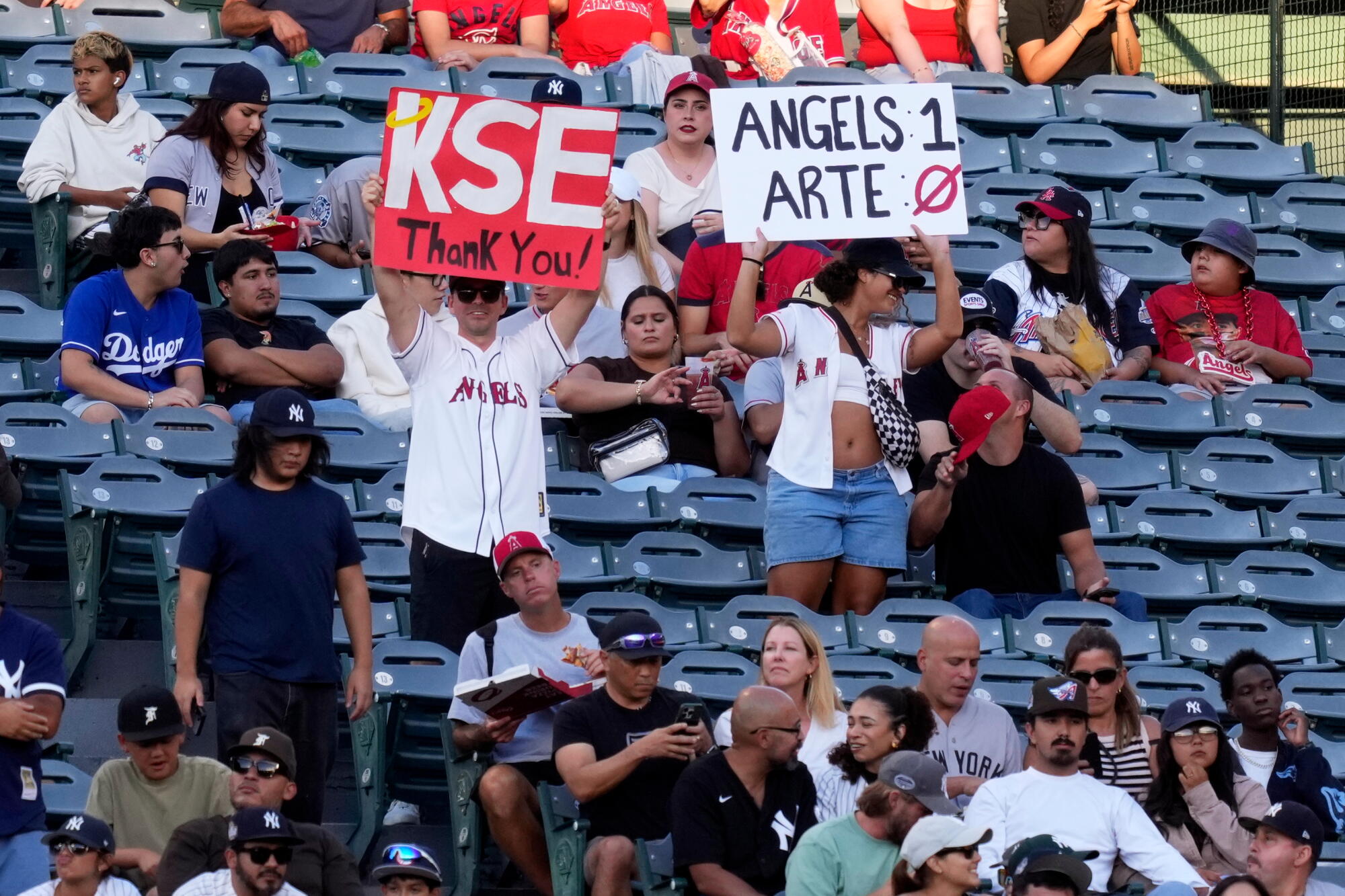 Fans hold up signs thanking Kroenke Sports and Entertainment for buying the Angels and taking a jab at Arte Moreno.