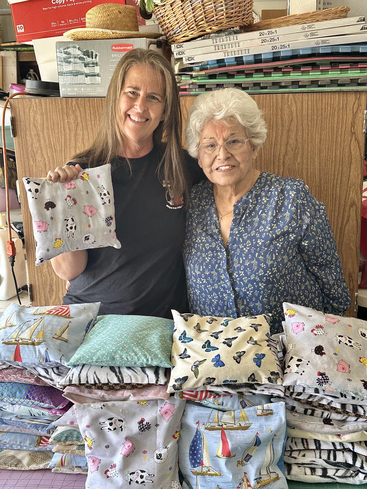 Shawnna Saldana and Genny Saldana pose with some of the completed kitten warming bags made by hand for WAGS Pet Adoption.