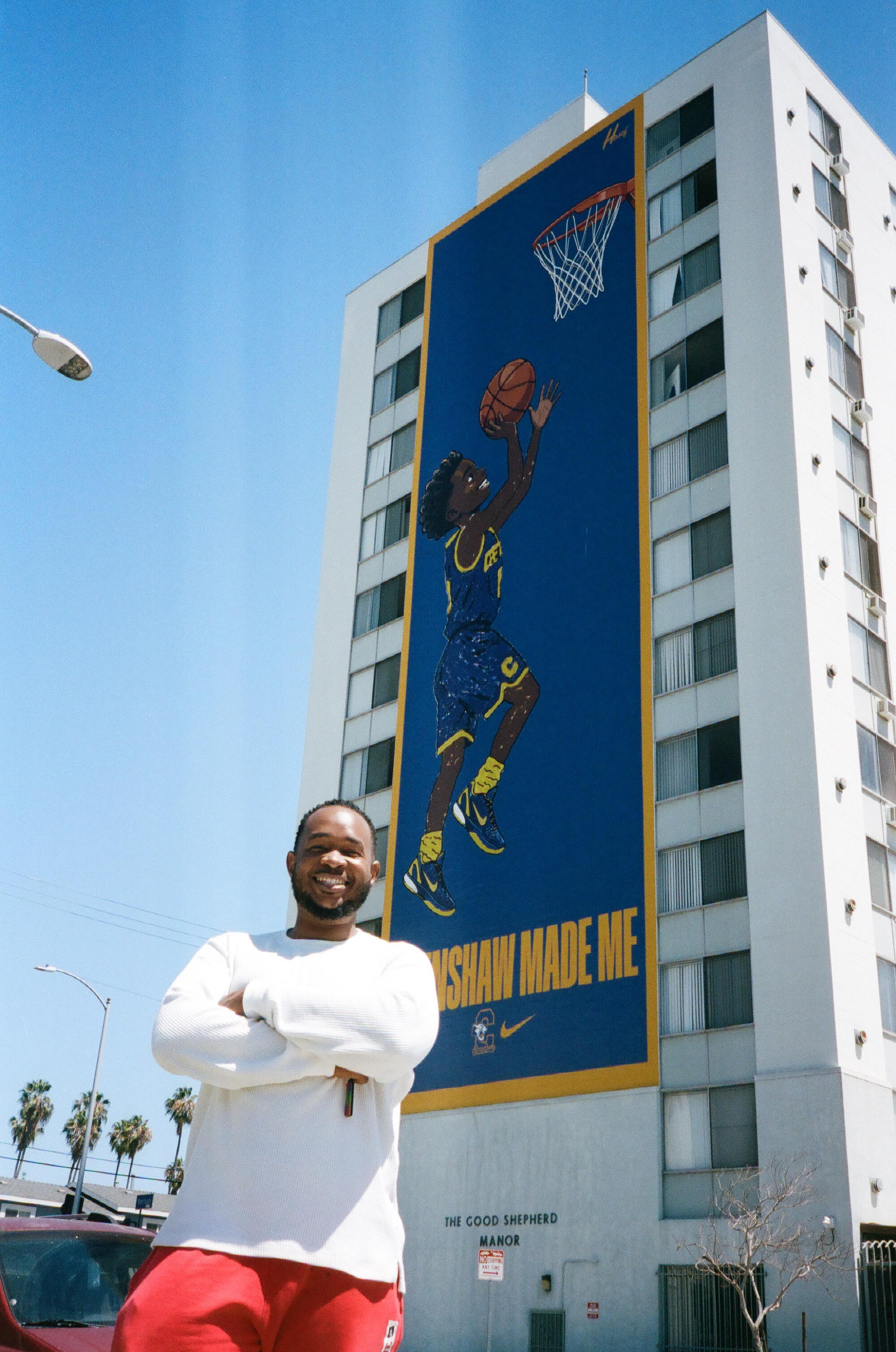 Jamal Hasef in front of his mural "Sky is the Limit," 2026 on 11th & Vernon in Leimert Park.