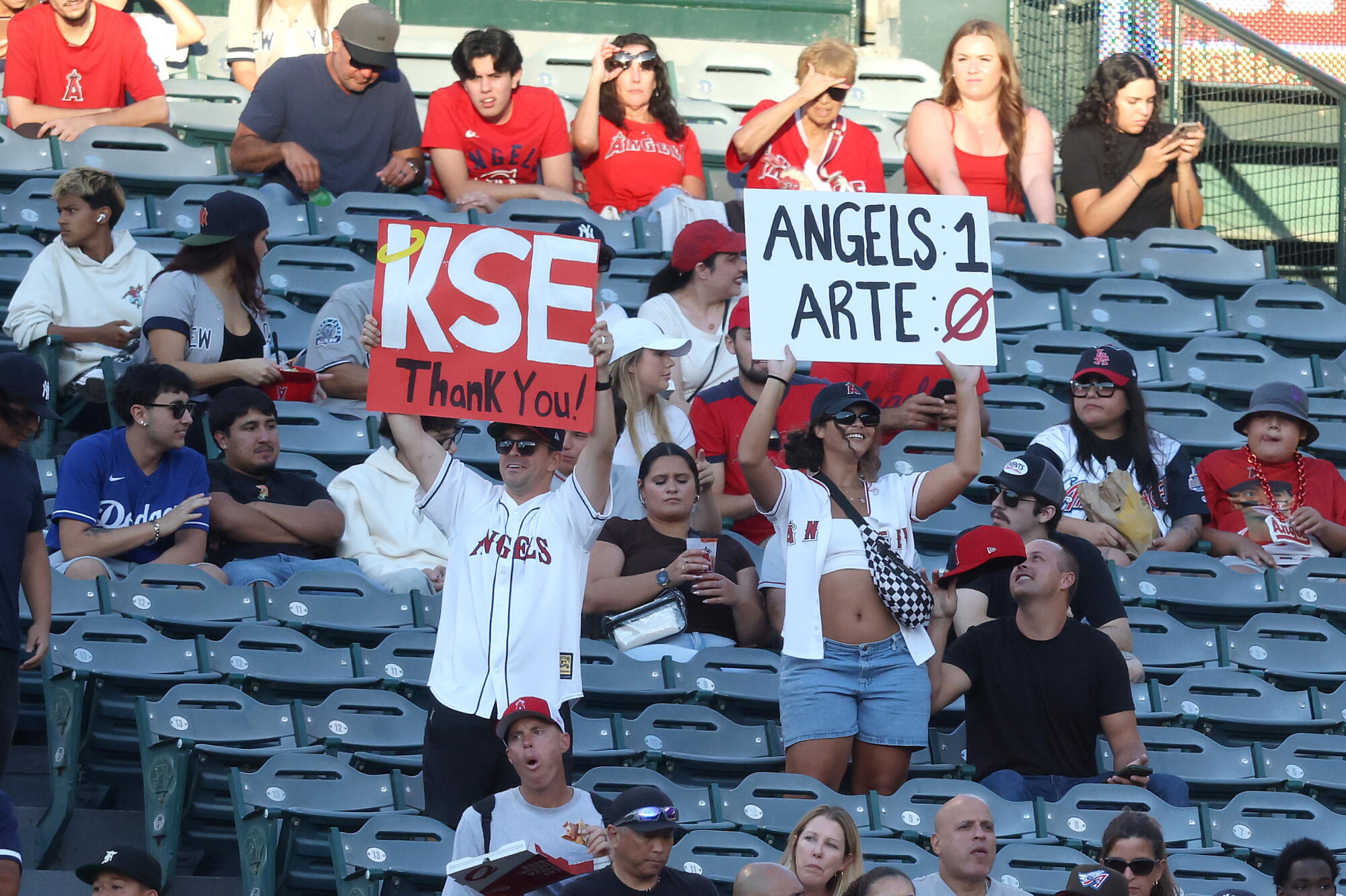 Angels fans hold up signs thanking Kroenke Sports and Entertainment for buying the team from Arte Moreno.