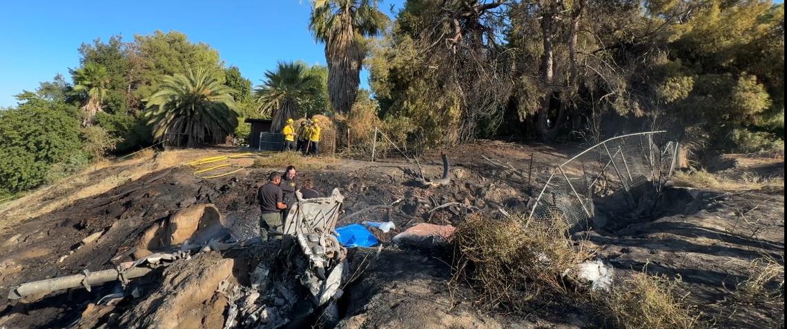 a river embankment with airplane wreckage and first responders
