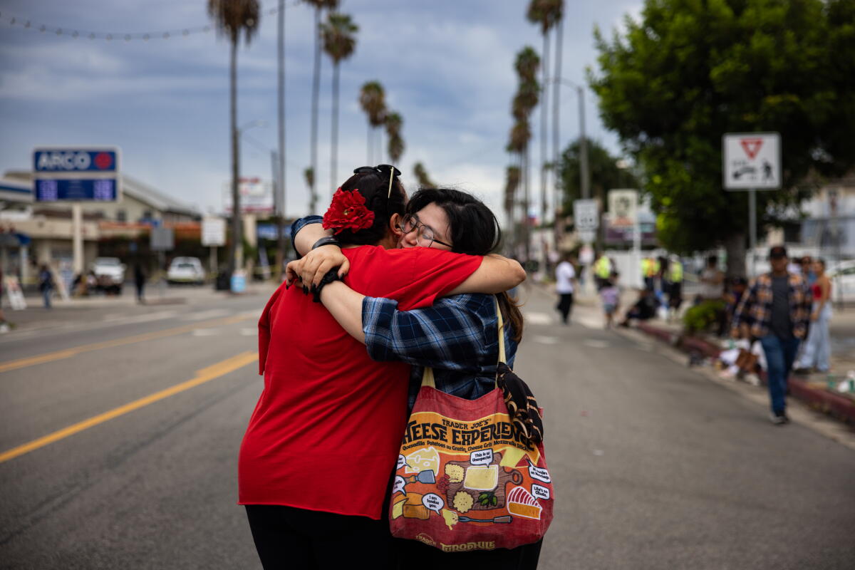 Giovanna Mendez, right, hugs a teacher during a Labor Day parade