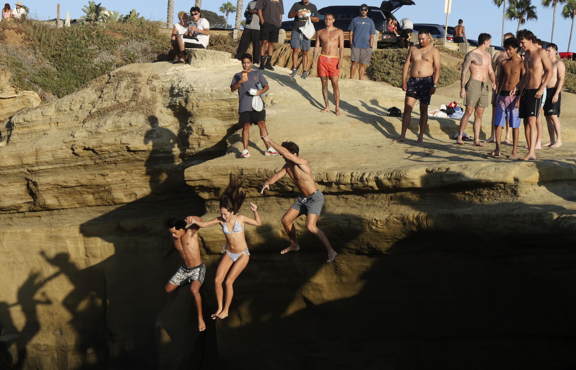 People jump into the water at Sunset Cliffs in the Ocean Beach area of San Diego
